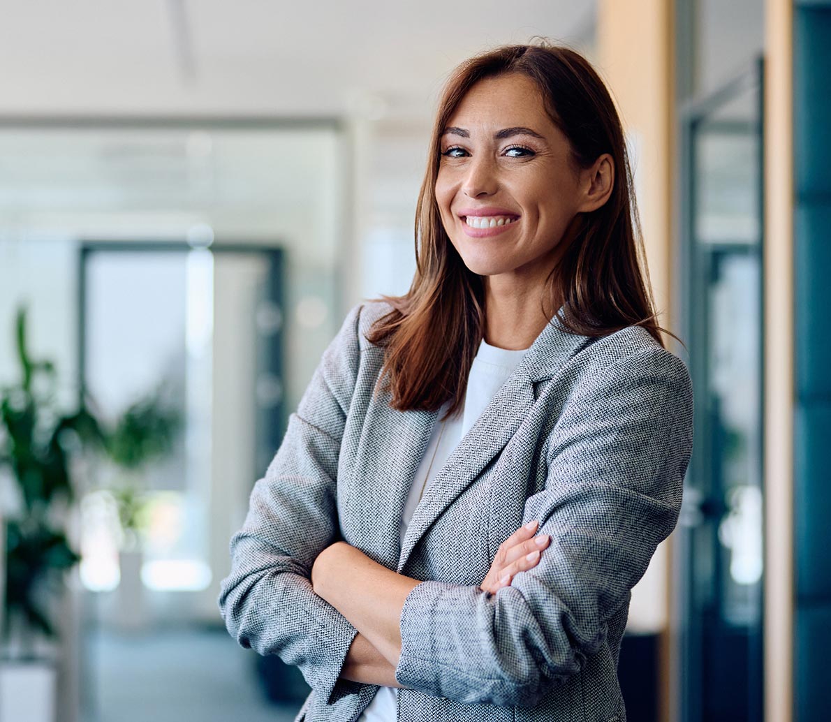 Strong independent business woman standing with arms crossed and looking at the camera, representing executive coaching and leadership development services at Mountain North Coaching and Consulting.